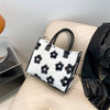 A black and white faux fur designer shoulder tote bag resting on a light-colored sofa.