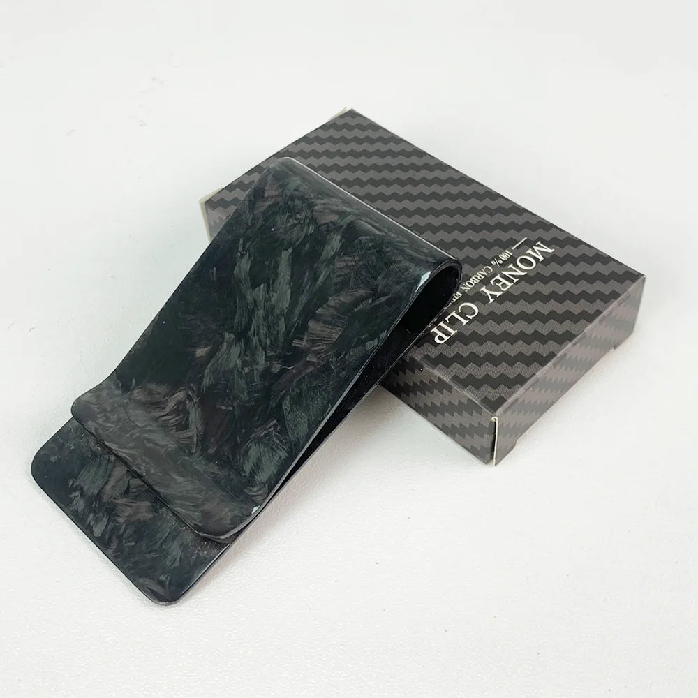 A black carbon fiber money clip is displayed next to its retail box.