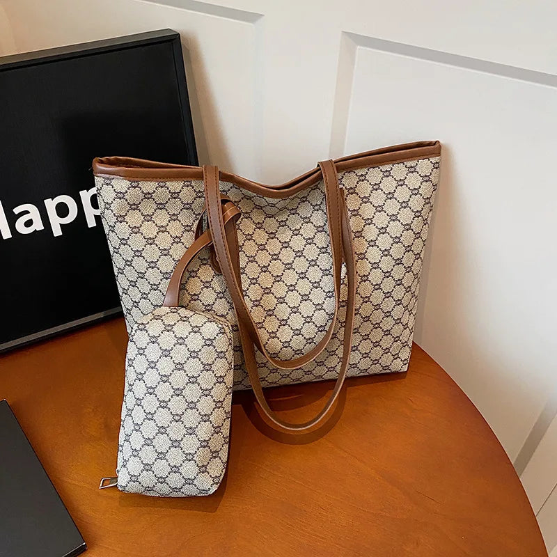 A beige and gray geometric patterned tote bag with brown leather trim resting on a wooden surface.