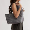 A woman holds a gray geometric patterned tote bag against a light background.