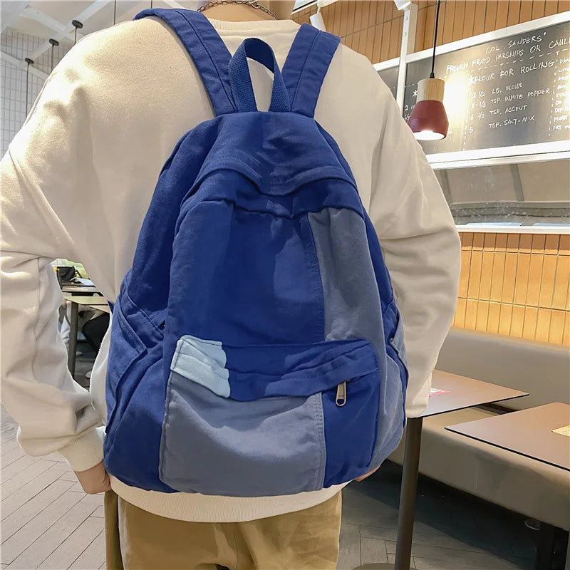 A blue canvas fashion backpack worn by a person, displayed in an indoor setting.