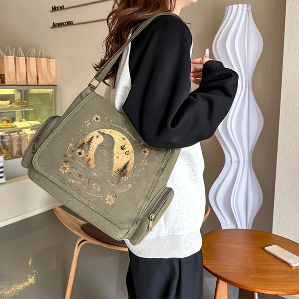 A woman holds a vintage canvas shoulder bag with an embroidered moon and tree design.