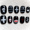 A set of press-on nails featuring various cartoon and gothic designs on black and white tips.