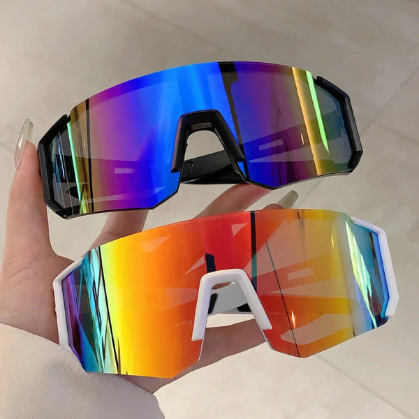 A hand holds a pair of lightweight oversized sunglasses with vibrant iridescent blue and orange lenses.