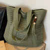 A close-up of a natural straw woven tote bag in olive green with leather trim and drawstring closure.