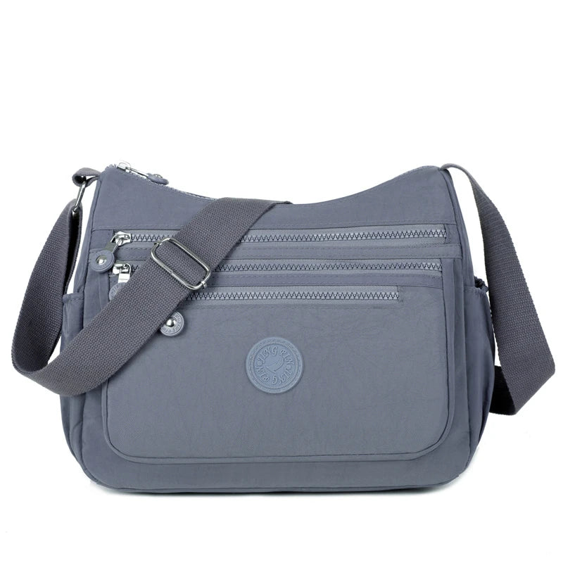 A gray waterproof nylon crossbody shoulder bag with a strap and a circular logo emblem.