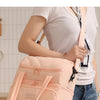 A woman is holding a light pink insulated lunch bag with a strap, demonstrating its use for carrying food.