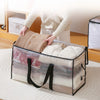 A person is placing a beige woven storage bag into a large transparent storage bag with black handles.