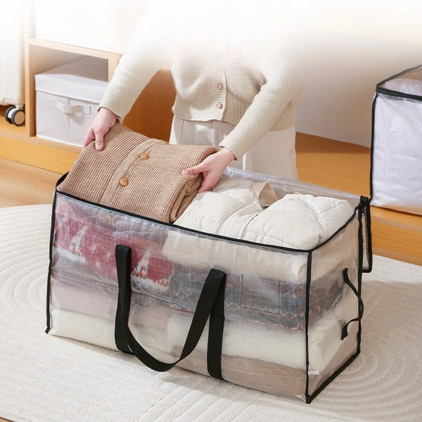 A person is placing a beige woven storage bag into a large transparent storage bag with black handles.