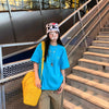 A person wearing a blue t-shirt and a patterned headband is walking down an outdoor metal staircase.