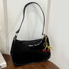 Black PU leather shoulder bag with a gold cherry pendant hanging from the strap.