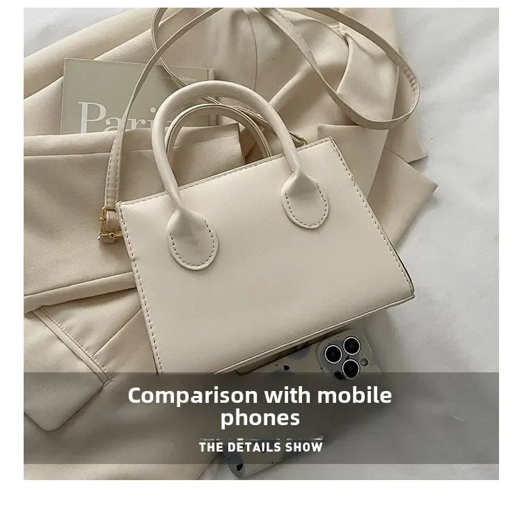 Sac à main en cuir PU beige clair minimaliste avec une poignée supérieure, à côté de téléphones mobiles.