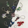A collection of hand sewn rhinestone beaded bag charms featuring various animal shapes like a snake, frog, star, and insects.