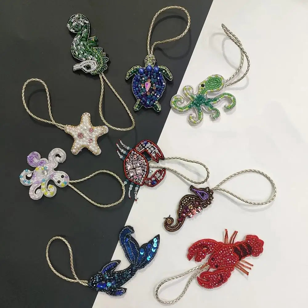 A collection of hand sewn rhinestone beaded bag charms featuring various animal shapes like a snake, frog, star, and insects.