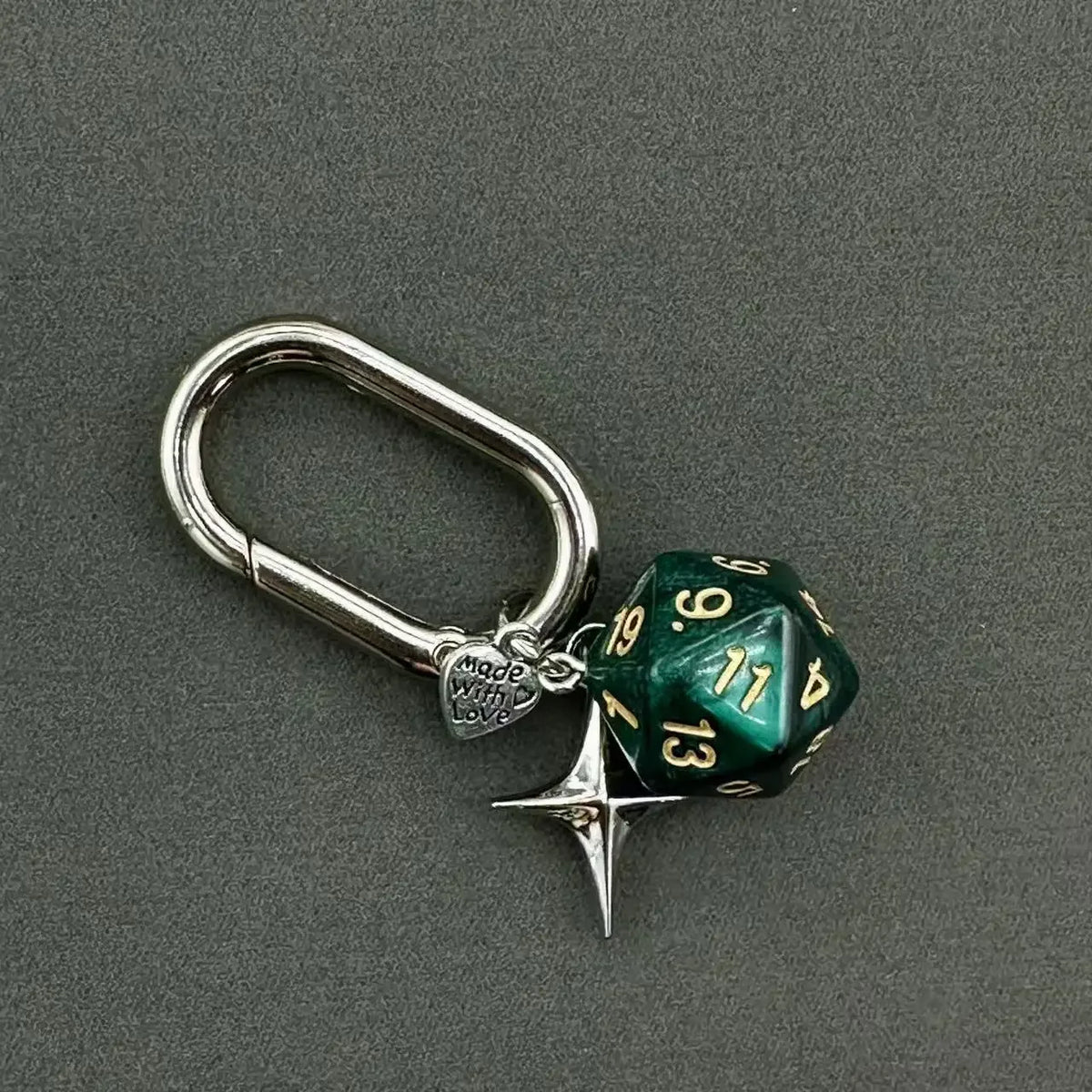 A silver keychain featuring a green resin die with the number 13 and a star charm.