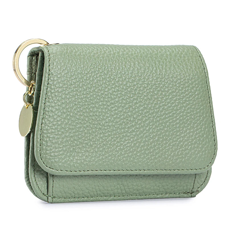 A light sage green genuine leather slim trifold wallet with a zipper pouch and gold hardware.