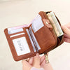 A brown RFID protected bi-fold wallet with a zipper closure is shown being held by a hand.