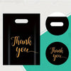 Black gift bags with gold script text Thank you displayed against a light background.