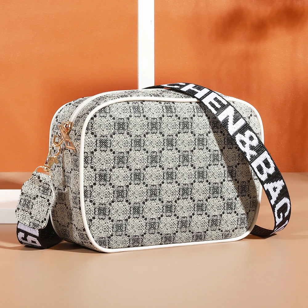 A beige and black patterned fashion crossbody shoulder bag with a white trim and black strap.