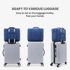 A blue foldable travel duffel bag is shown with a luggage strap, next to a silver suitcase.