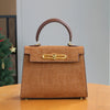 A tan leather tote bag with a crocodile pattern and gold hardware sitting on a wooden table.