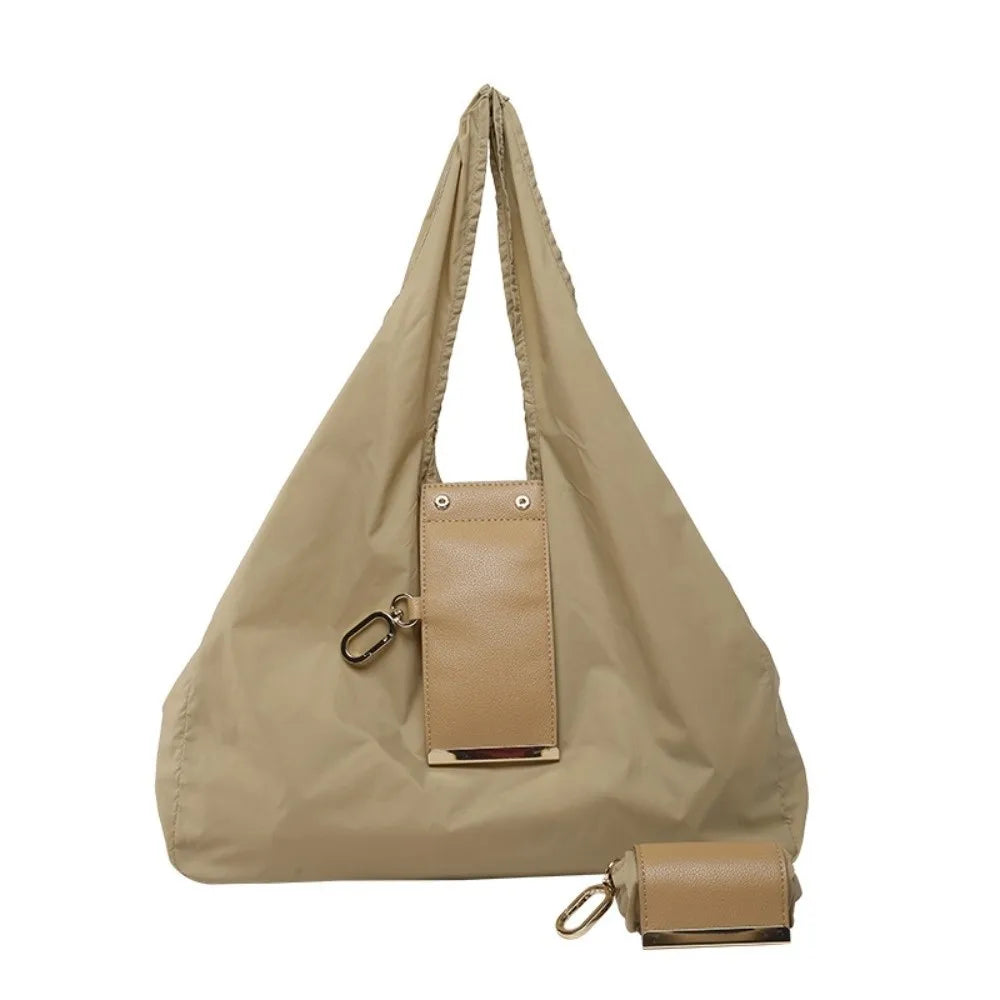 A beige reusable nylon mini keychain tote bag with a leather strap and attached leather pouch.