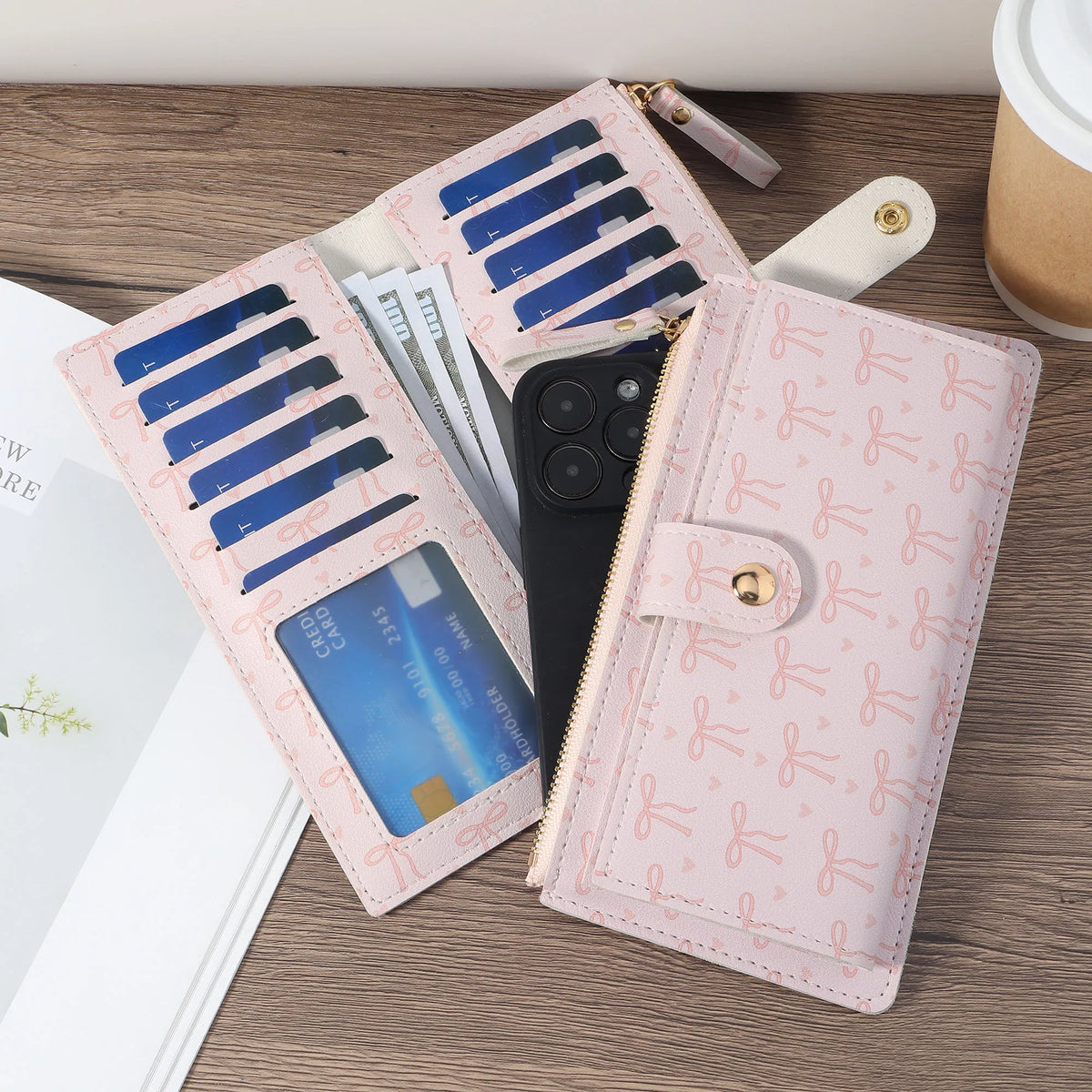 A pink folding multi-card wallet with blue accents and a black phone case is displayed on a wooden surface.