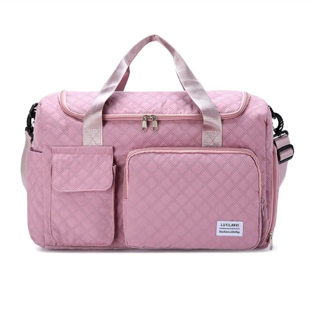 A pink quilted portable travel duffle bag with light pink straps and zipper details.