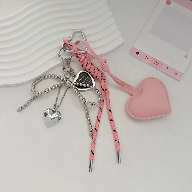 A collection of pink and silver bow keychains and charms displayed on a white surface.