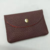 A dark burgundy genuine leather card holder with a stitched edge and a round gold-toned clasp.