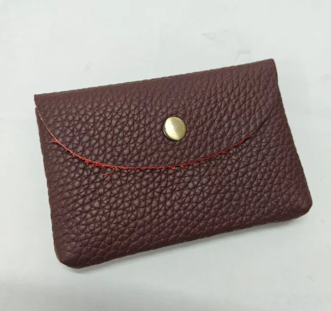 A dark burgundy genuine leather card holder with a stitched edge and a round gold-toned clasp.