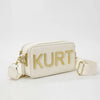 A cream leather tote bag with gold lettering spelling out KURT