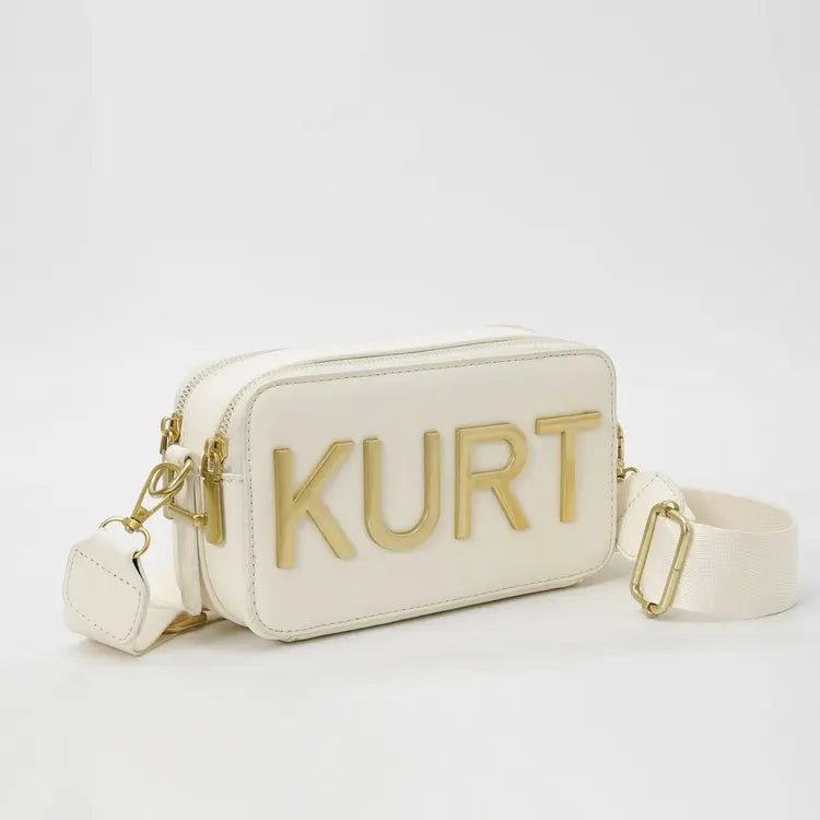A cream leather tote bag with gold lettering spelling out KURT