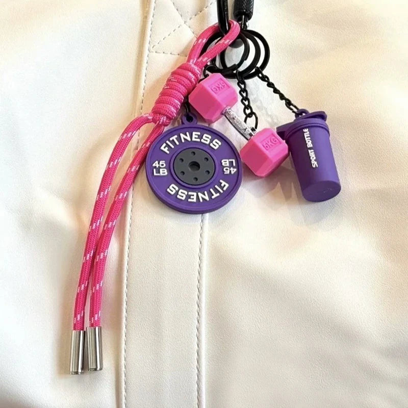 A pink fitness keychain with purple and pink components attached to a white leather surface.