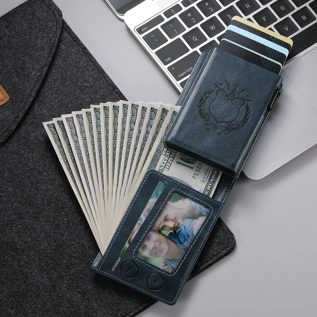 A dark blue anti-RFID blocking PU leather card holder with a leather sleeve and a photo holder resting on a laptop.