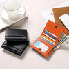 An orange RFID-blocking bi-fold wallet with a carbon fiber finish is shown next to a black leather wallet and a white cup.