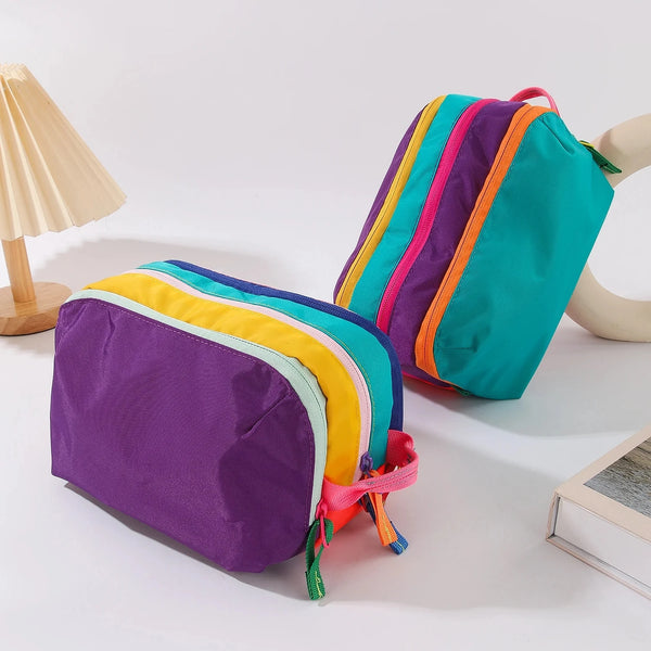 Un sac de maquillage de voyage coloré et léger avec plusieurs compartiments violets, jaunes, roses et turquoise.