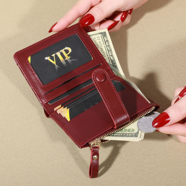 A maroon PU leather card wallet with a VIP embossed flap and a double zip closure, held by a hand next to US currency.