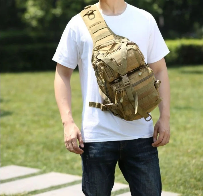 A person wearing a white t-shirt is holding a tan sling backpack.