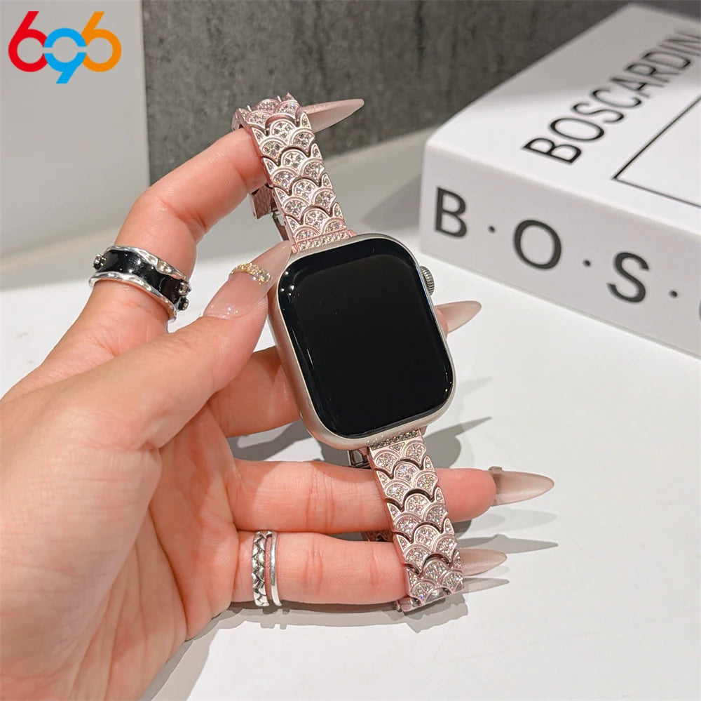 A hand is holding a black Apple Watch with a sparkling crystal fishscale metal band.