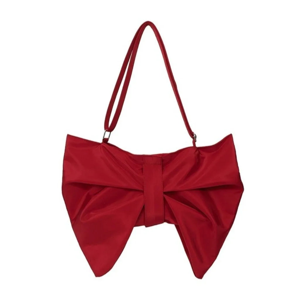 A vibrant red pleated bow crossbody tote bag.