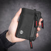 A hand holds a black RFID blocking travel wallet with an attached carabiner.