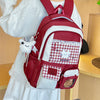 A red backpack with white accents and a checkered patch on the front is worn by a person.