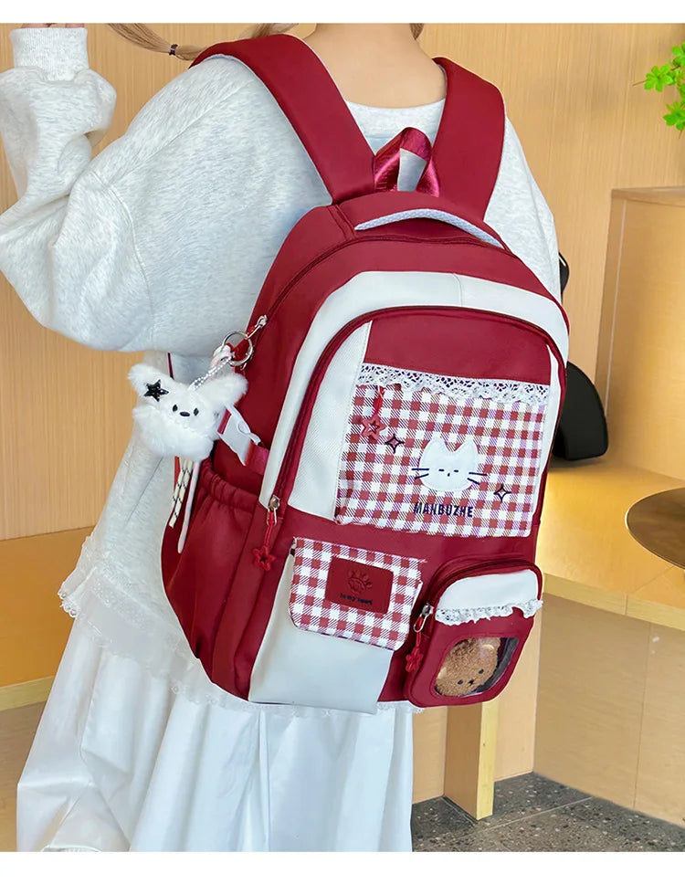 A red backpack with white accents and a checkered patch on the front is worn by a person.