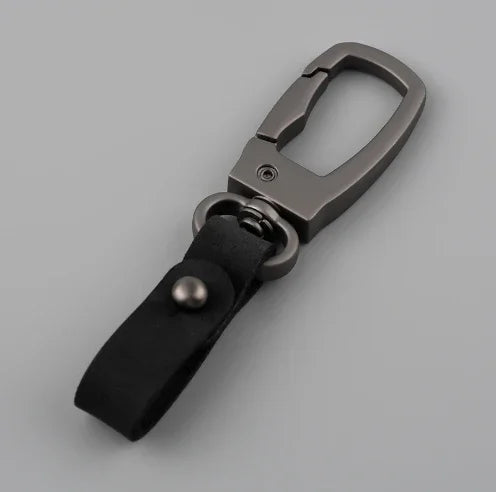 A close-up view of a genuine leather keyring keychain with a metal clasp and black leather strap.
