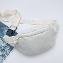 A white nylon crossbody sling bag with a light beige strap is shown against a white background.