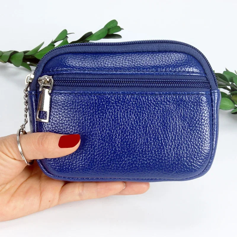 A hand holds a dark blue PU leather mini wallet with a silver keychain against a white background.