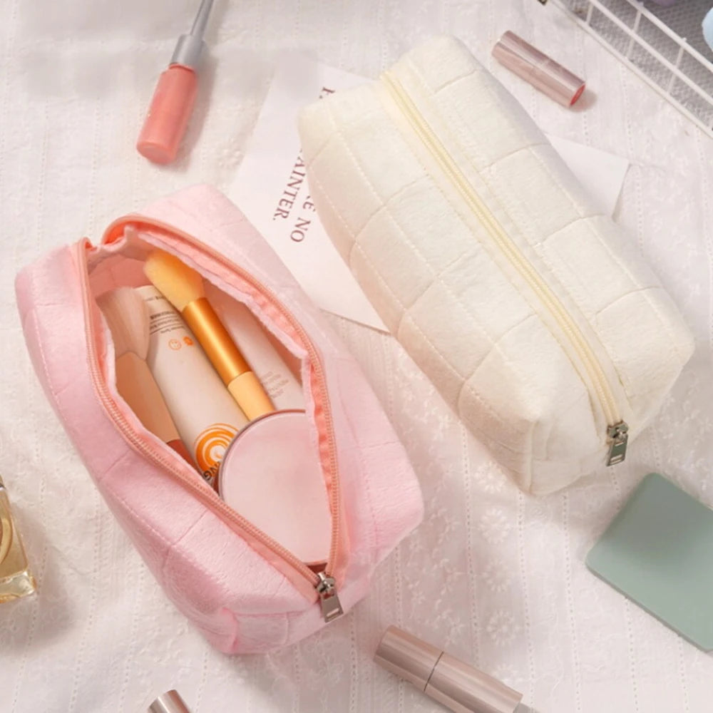 A quilted pink velvet cosmetic and toiletry bag open to show makeup brushes and a palette