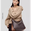 A model wears a beige knit sweater and carries a geometric embroidery hobo shoulder bag.