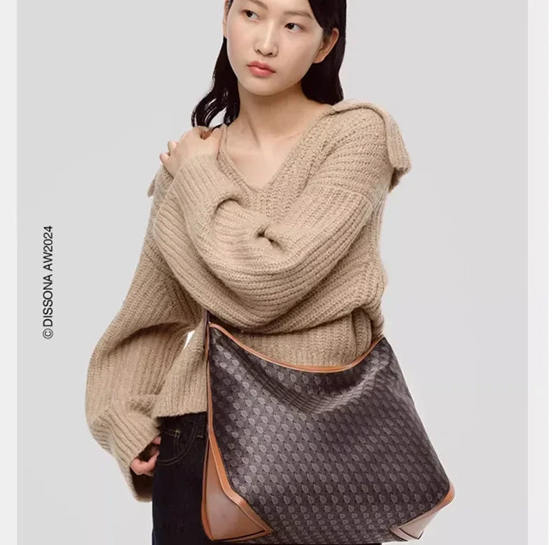 A model wears a beige knit sweater and carries a geometric embroidery hobo shoulder bag.